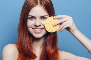 Güzel bir kadın, çıplak omuzlar, cazibeli bir sünger, mavi arka planda.