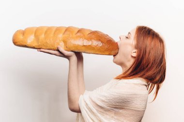 Aç bir kadın büyük bir somun ekmek yiyor. Somun somunu yan görüş arka planında.