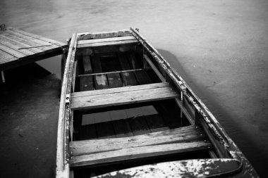 Nehirde eski ahşap bir tekne iskelenin yanında.