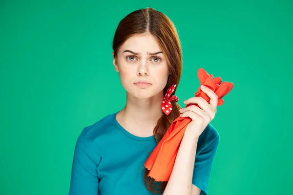 Hausfrau hält Handschuhe in den Händen Grüner Hintergrund häusliche Pflege — Stockfoto