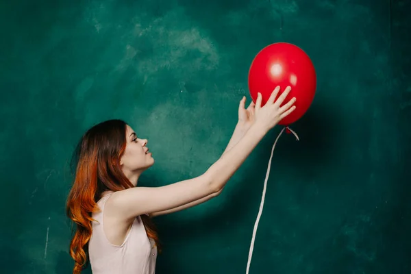 女人手里拿着一个充气红球，手里拿着绿色背景的节日礼物 — 图库照片