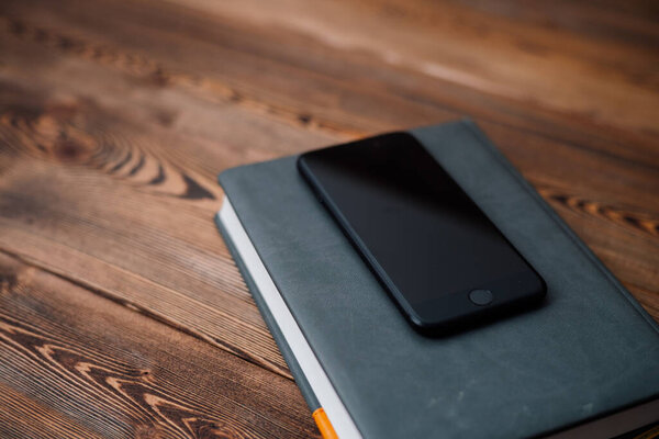 mobile phone and book with cover on wooden background