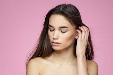 Esmer, çıplak omuzlar, temiz cilt bakımı pembe arka plan.