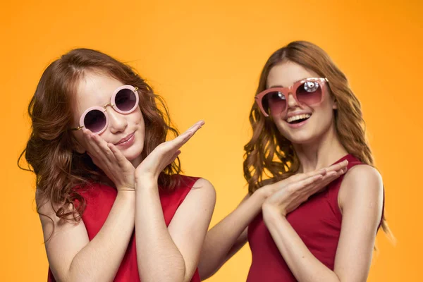 Dwie siostry i zabawne okulary moda Przyjaźń żółty tło rodzina — Zdjęcie stockowe