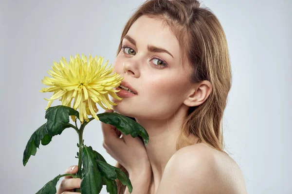 Retrato de uma mulher bonita com uma flor amarela em um fundo leve encantador sorriso modelo de cabelo vermelho — Fotografia de Stock