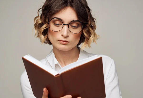 Femme avec un bloc-notes dans les mains et portant des lunettes sur un fond gris vue recadrée d'une chemise Light — Photo