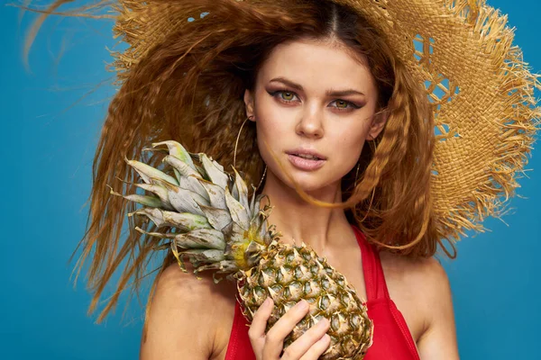 En kvinna i halmhatt med en ananas i händerna eller är det en rolig blå exotisk frukt bakgrund — Stockfoto