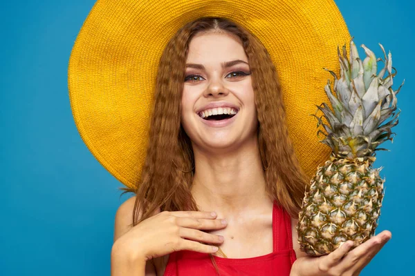 Frau mit gelbem Hut mit Ananas in den Händen Emotionen Spaß Lifestyle Sommer Obst blauer Hintergrund — Stockfoto