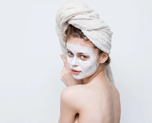 Bella donna con asciugamano sulla maschera crema testa sul viso da vicino — Foto Stock