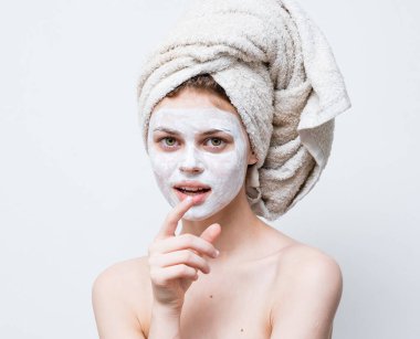 Bir kadın görünüşüne önem verir ve kafasında bir havlu ve yüzünde bir nemlendirici.