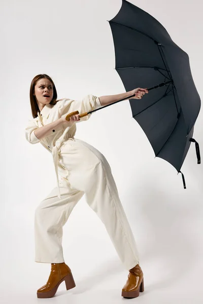 白いスーツの女性は、風から傘を保持します現代的なスタイルのファッションスタジオ — ストック写真