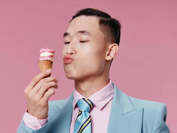 スーツの男はコーンでアイスクリームを調べますプロの試飲ピンクの背景 — ストック写真