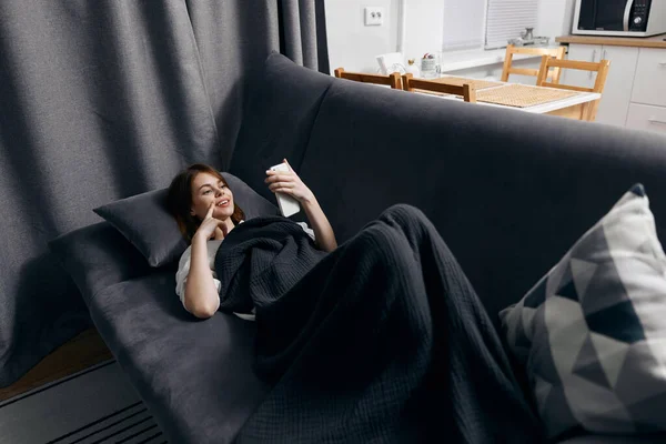 Mulher com telefone na mão descansando deitado no sofá vista superior — Fotografia de Stock