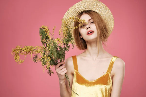 Vacker kvinna i en hatt gyllene klänning buketter av blommor semester — Stockfoto
