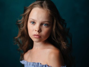 Saçları kıvırcık, omuzları açık güzel bir kızın portresi.