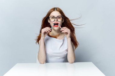 Çekici kızıl saçlı kadın masada oturuyor ve gözlüklü reçel yiyor.