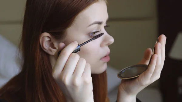 Жінка малює вії дзеркалом в руці жіночність догляду за собою — стокове фото