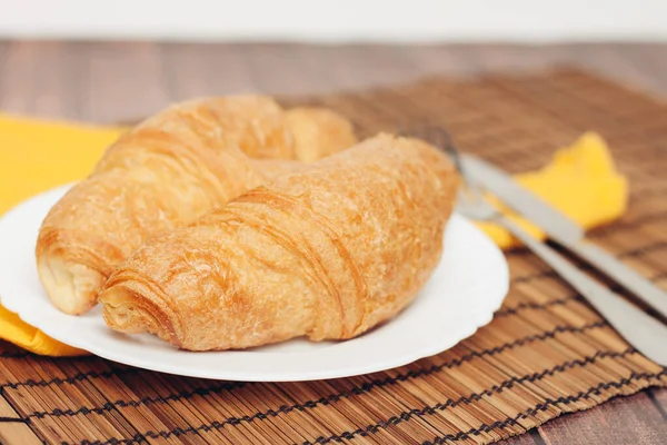 Krispiga croissanter på tallrik köksredskap till frukost måltid dessert — Stockfoto