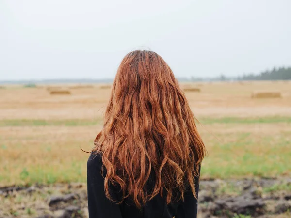 野原の屋外で黒いドレスを着た赤い髪の美しい女性 — ストック写真