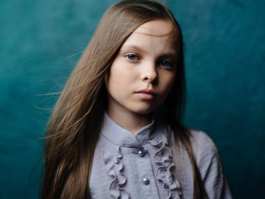 Turkuaz arka planda gri elbiseli bir kızın portresi gevşek saçlarının yakın plan çekimi.