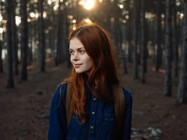 Femme heureuse en chemise bleue voyage dans une forêt de pins et le coucher du soleil au loin — Photo