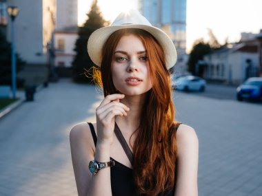 Beyaz şapkalı, siyah elbiseli, kırmızı saçlı güzel bir kadın.