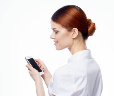 Beyaz gömlekli güzel kadın. Elinde telefon, teknoloji iletişimi olan sekreter.