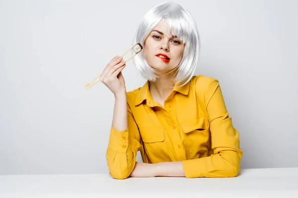 Ελκυστική γυναίκα με λευκή περούκα που τρώει σούσι. — Φωτογραφία Αρχείου