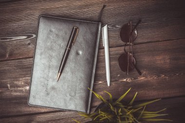 Not defteri bardakları ve saksıda bir çiçek Tahta bir masanın üstünde kalem ofisi