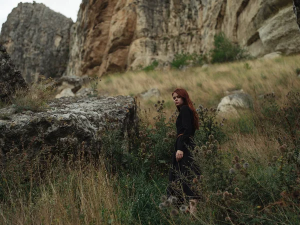 Una mujer en un vestido negro están caminando en las montañas en la naturaleza en otoño —  Fotos de Stock