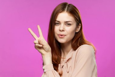 Güzel bir kadın elleriyle jest yapıyor. Modayı büyülüyor. Pembe arka plan.