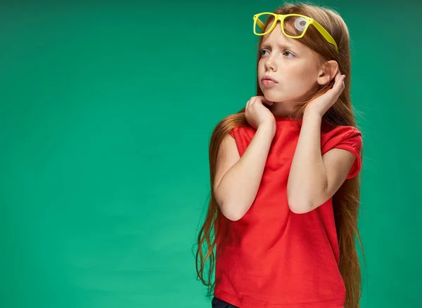 Χαριτωμένο κορίτσι με κόκκινα μαλλιά με γυαλιά στο κεφάλι κόκκινο t-shirt Studio Πράσινο φόντο — Φωτογραφία Αρχείου