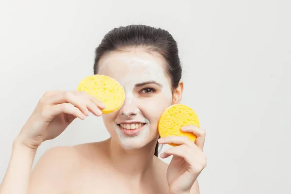 Wanita cantik dengan bahu telanjang menyeka topeng dengan spons kulit bersih — Stok Foto