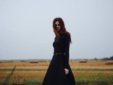 Tarlada siyah elbiseli, kızıl saçlı güzel bir kadın.