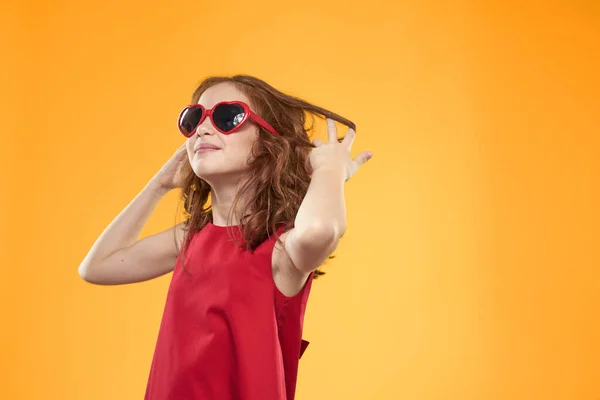 Siyah gözlüklü kız kırmızı elbise çocukluk eğlencesi sarı arka plan — Stok fotoğraf