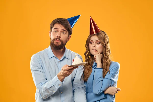 Homme et femme heureux avec gâteau d'anniversaire sur fond jaune — Photo