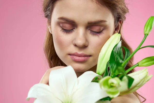 White flowers in female hands on a pink background portrait cropped view of model makeup