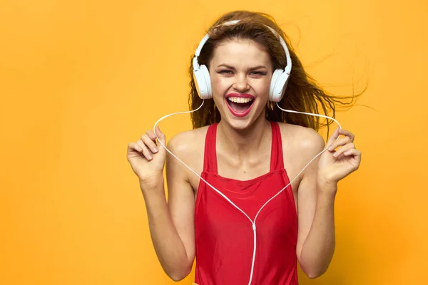 Mulher alegre em fones de ouvido ouve música em um fundo vermelho T-shirt amarelo — Fotografia de Stock
