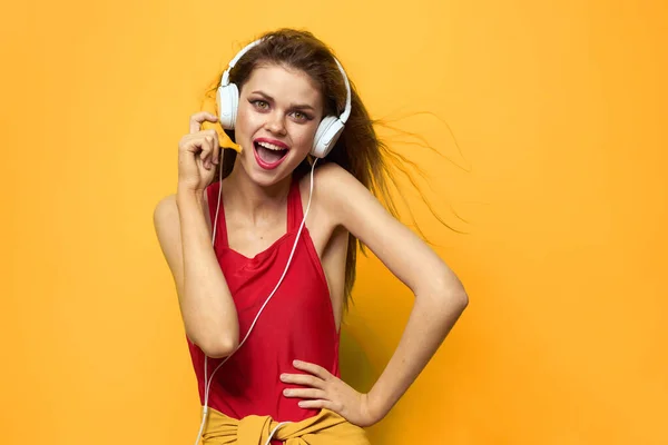 ผู้หญิงในหูฟังฟังฟังเพลงเสื้อยืดสีแดงอารมณ์แฟชั่นพื้นหลังสีเหลืองไลฟ์สไตล์ — ภาพถ่ายสต็อก