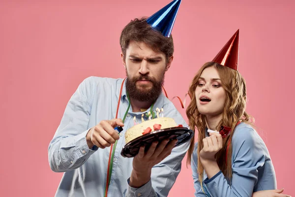 Festa homem e mulher com bolo no fundo rosa aniversário corporativo — Fotografia de Stock