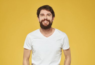 Beyaz tişörtlü bir adam ellerini sarı arka planda gezdirir.