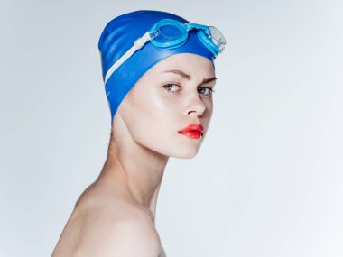 Açık arkaplanda bir kadın yüzücü portresi, çıplak omuzlar ve kırmızı dudaklar.