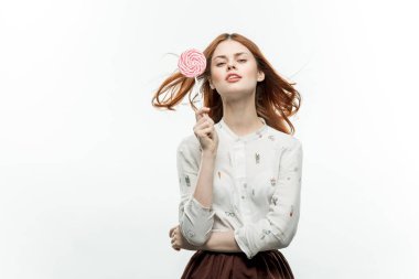 Ellerinde lolipopu olan kızıl saçlı güzel bir kadın. Duygularını atölyeye yöneltti.