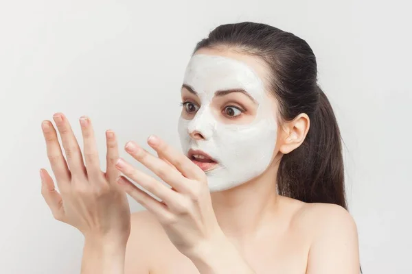 brunette with cream face mask skin care brush applying makeup