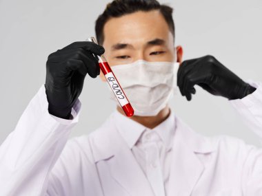 Erkek laboratuvar asistanı tıbbi maske siyah eldiven kan testi araştırması