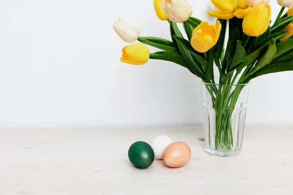 教堂的传统复活节彩蛋和一束鲜花放在一个浅背景的花瓶里 — 图库照片