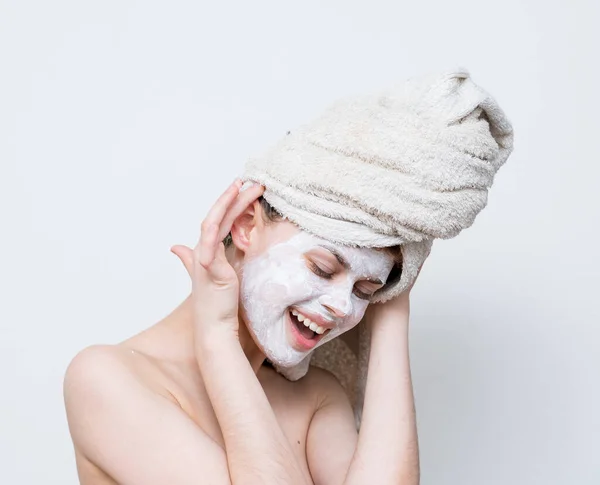 Kobieta z ręcznikiem na głowie gołe ramiona biała maska na twarzy pielęgnacja skóry — Zdjęcie stockowe