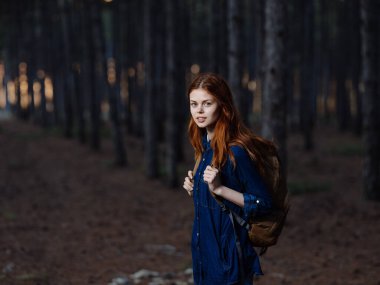 Sırt çantalı bir kadın turist ormanda doğa yürüyüşü yapıyor.