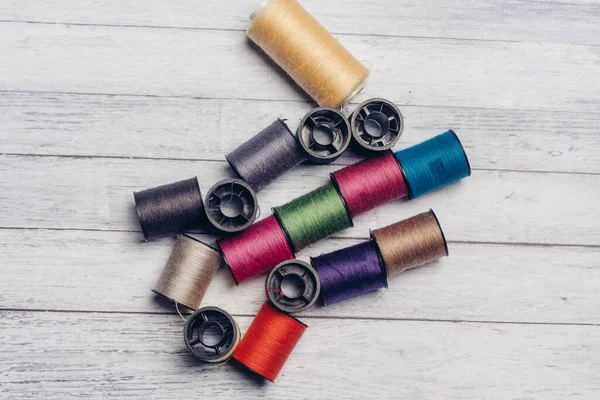 Sewing accessories colored threads top view wooden background — Stock Photo, Image