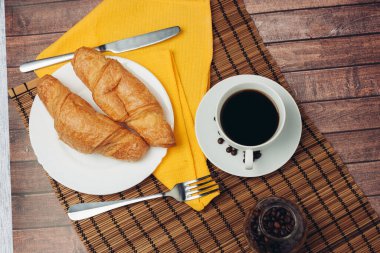 çay tabağında taze kruvasanlar kahvaltı bardağını içeceklerle dolduruyor.